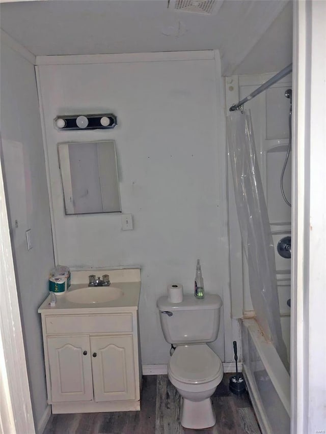 bathroom featuring wood finished floors, vanity, toilet, shower / bath combo with shower curtain, and baseboards