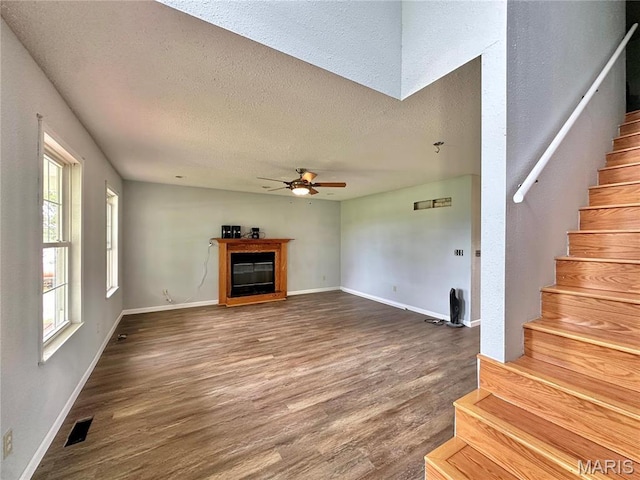 6624 State Route C, Saint Genevieve, MO 63670 - unfurnished living room with wood finished floors, stairs, a ceiling fan, a textured ceiling, and a glass covered fireplace