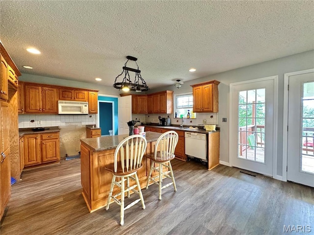 6624 State Route C, Saint Genevieve, MO 63670 - kitchen featuring white appliances, wood finished floors, a center island, a textured ceiling, and brown cabinets