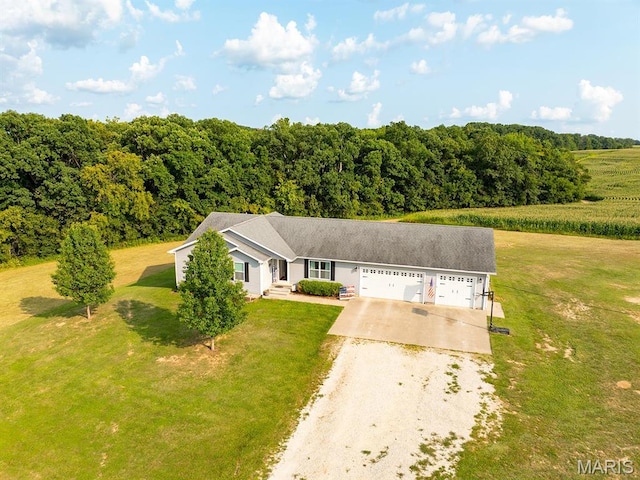 view of front of property featuring concrete driveway, a front yard, an attached garage, and a wooded view