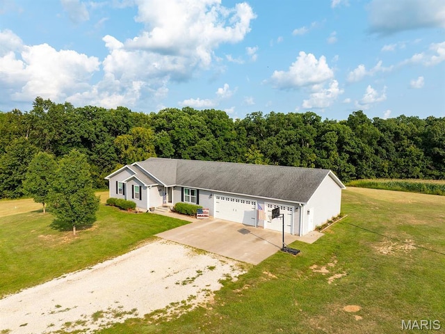 ranch-style house featuring driveway, an attached garage, a front lawn, and a wooded view