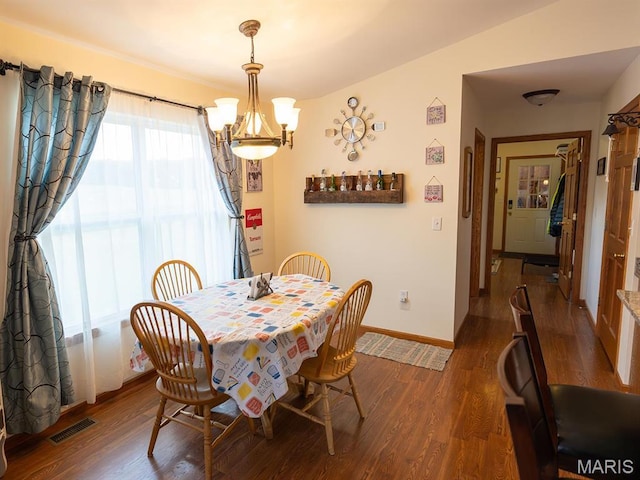 dining room featuring a chandelier, wood finished floors, and baseboards