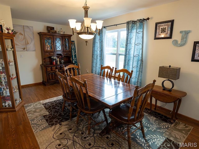 dining space with wood finished floors, a chandelier, and baseboards
