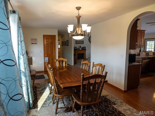 dining space with arched walkways, dark wood-style flooring, a chandelier, and baseboards