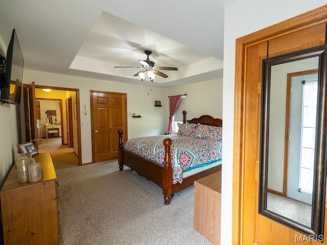 bedroom featuring a raised ceiling, carpet flooring, a ceiling fan, and baseboards