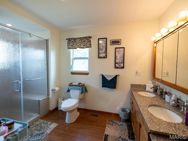full bath with wood finished floors, a stall shower, toilet, and double vanity