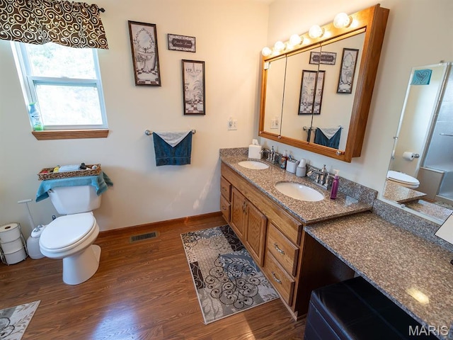 full bath with wood finished floors, toilet, double vanity, and baseboards