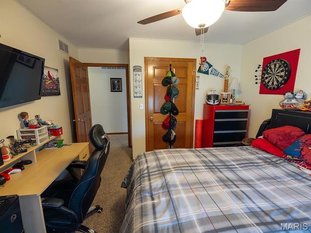 carpeted bedroom with ceiling fan and an office area
