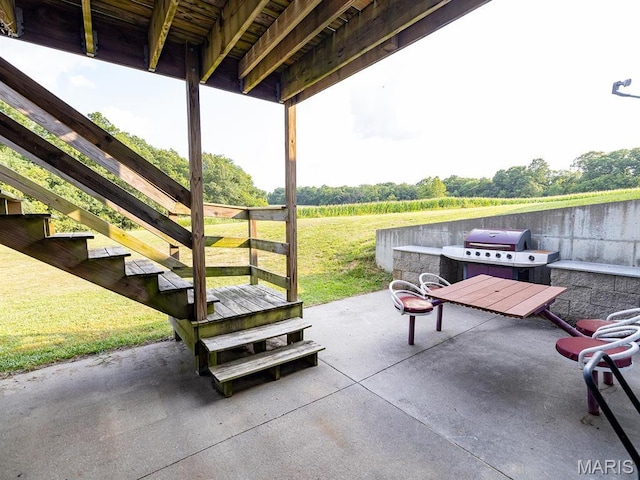 view of patio with stairs, a view of countryside, and grilling area