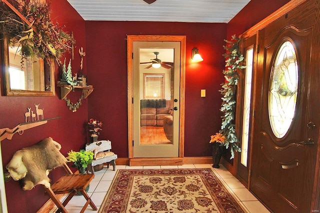 foyer with a ceiling fan, light tile patterned flooring, plenty of natural light, and baseboards