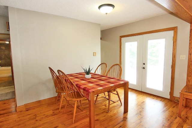 dining space with light wood finished floors, french doors, and baseboards