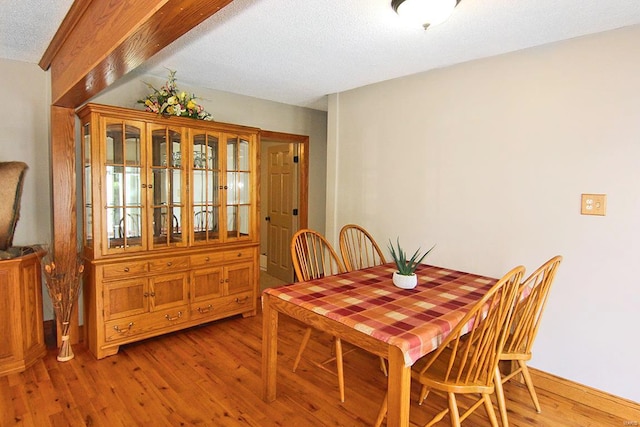 dining area featuring light wood finished floors and a textured ceiling