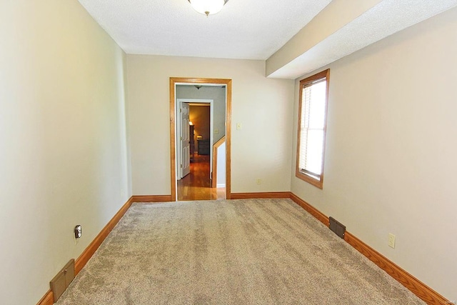 spare room featuring carpet flooring and baseboards