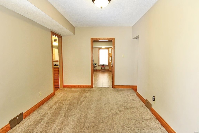 empty room with carpet, baseboards, and a textured ceiling