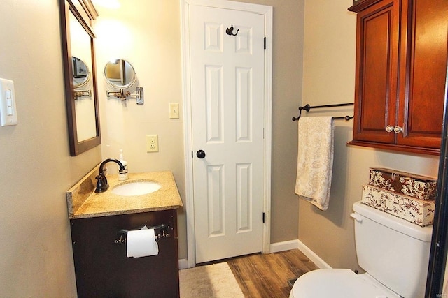 bathroom with wood finished floors, toilet, vanity, and baseboards