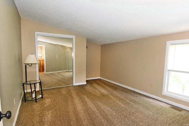 carpeted spare room featuring baseboards and vaulted ceiling