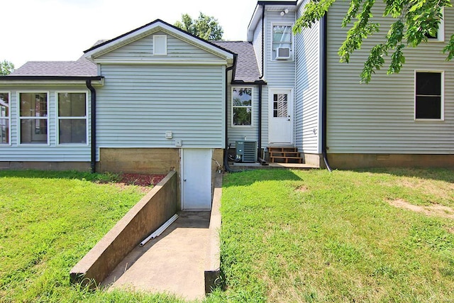 rear view of property with entry steps, a yard, central air condition unit, and roof with shingles