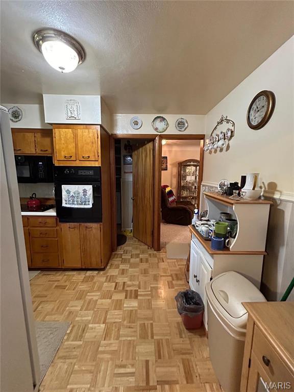 102 W Center St, Salem, MO 65560 - kitchen featuring black appliances, brown cabinets, and a textured ceiling