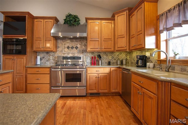 970 Lammert Ln, Union, MO 63084 - kitchen featuring stainless steel appliances, wall chimney range hood, a sink, light wood-type flooring, and tasteful backsplash