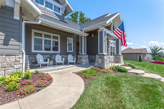 128 Jared St, Waynesville, MO 65583 - view of exterior entry with covered porch, stone siding, a yard, and a shingled roof