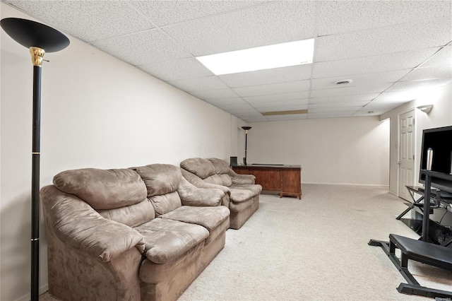 living room featuring light colored carpet, a drop ceiling, and baseboards