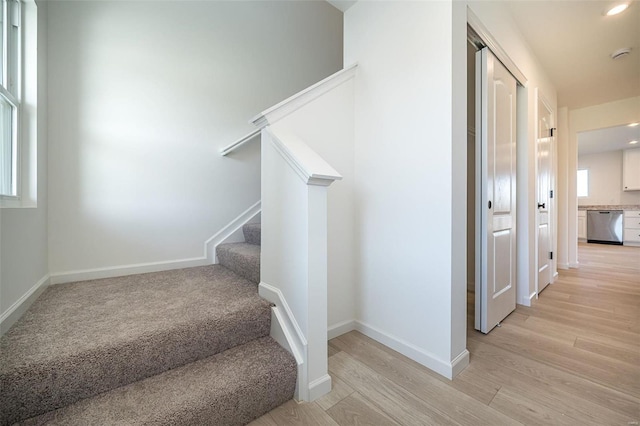 stairway featuring wood finished floors, baseboards, and recessed lighting