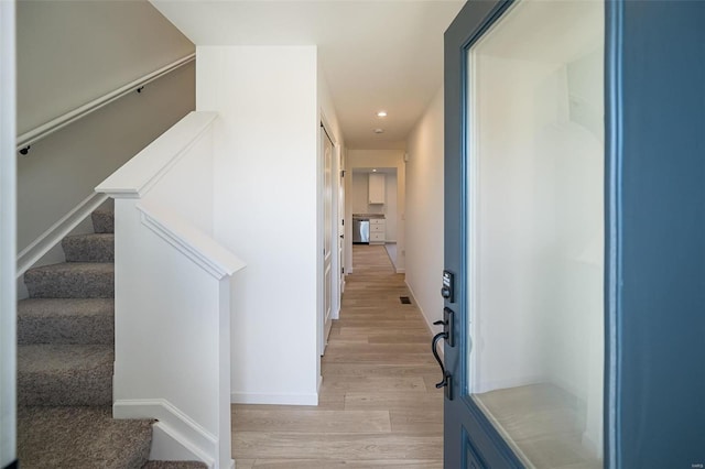 hallway featuring light wood-style floors, recessed lighting, stairway, and baseboards