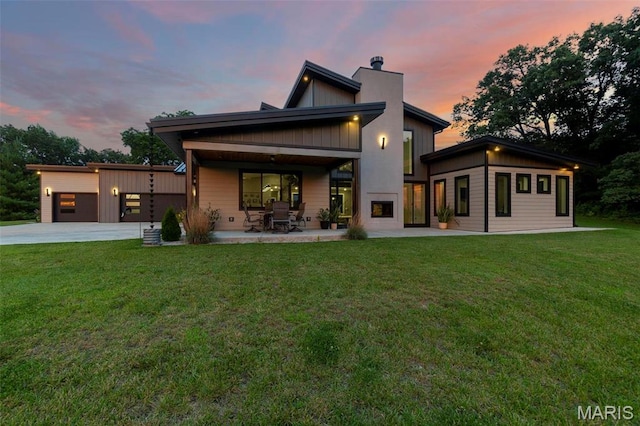 173 Tate Rdg, Cape Girardeau, MO 63701 - back of property at dusk with a chimney, a yard, driveway, a patio area, and an attached garage