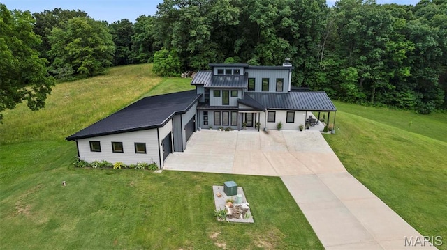 173 Tate Rdg, Cape Girardeau, MO 63701 - rear view of house featuring driveway, a chimney, a yard, a view of trees, and a garage