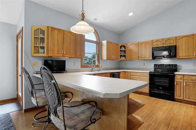 7102 Shadow Ln, Villa Ridge, MO 63089 - kitchen featuring black appliances, a sink, a kitchen breakfast bar, light wood-style flooring, and glass insert cabinets