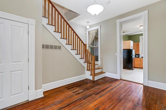 foyer entrance featuring hardwood / wood-style flooring, baseboards, and stairway