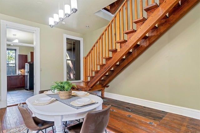 dining area with wood-type flooring, baseboards, stairs, and a chandelier