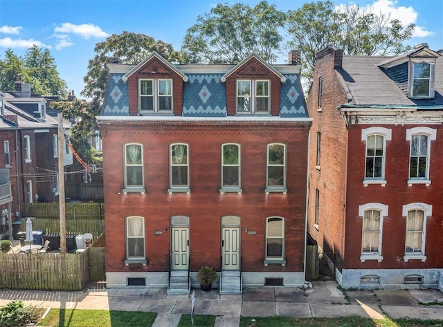view of front facade with entry steps, fence, a chimney, and mansard roof