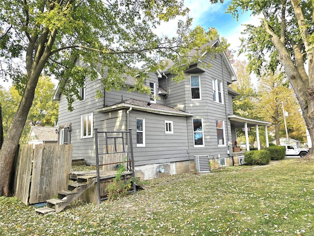 view of home's exterior featuring a lawn, roof with shingles, central AC, and a porch