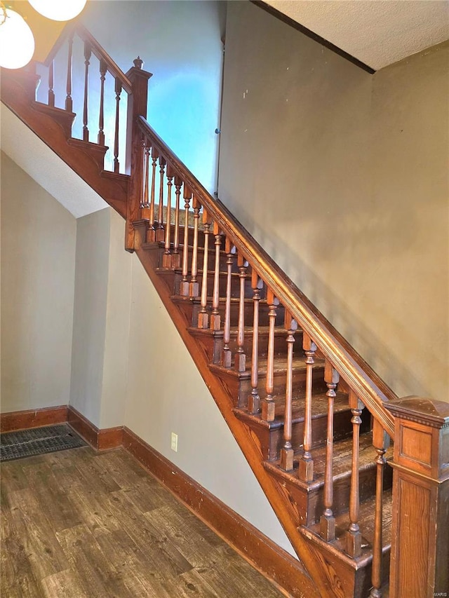 stairway with wood finished floors and baseboards