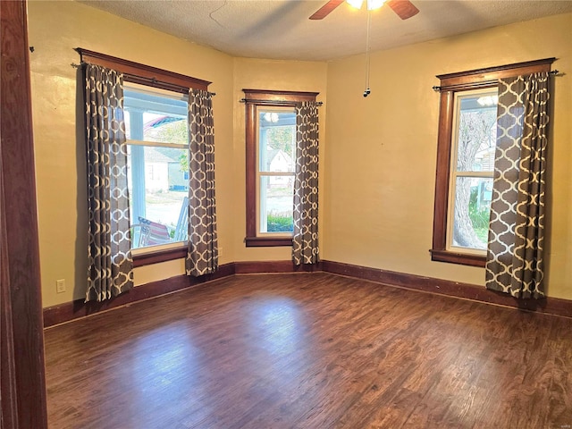 spare room featuring wood finished floors, ceiling fan, baseboards, and a textured ceiling