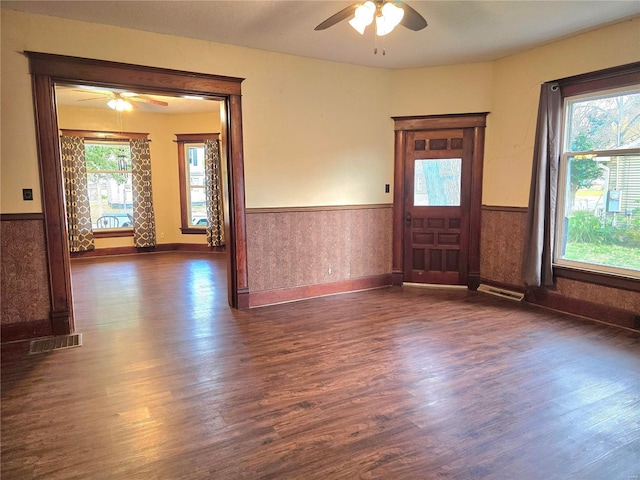 unfurnished room with ceiling fan, wainscoting, dark wood-type flooring, and baseboards
