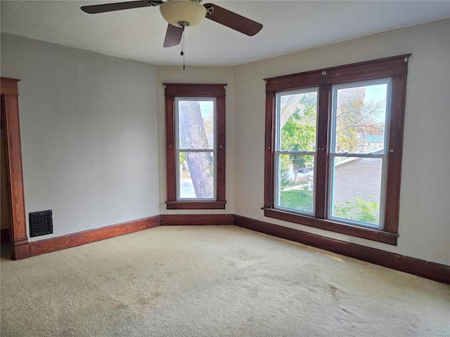 carpeted empty room with baseboards and a ceiling fan