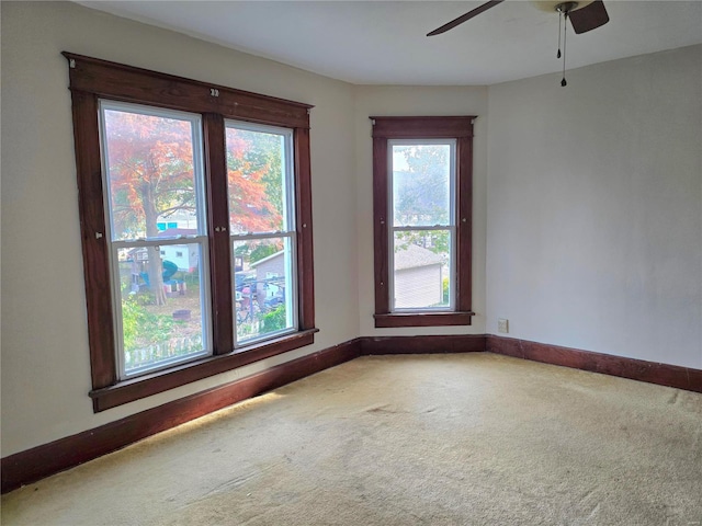 empty room featuring carpet flooring, a ceiling fan, and baseboards