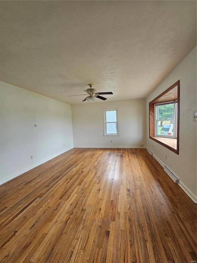 unfurnished room featuring wood finished floors, baseboards, and a ceiling fan