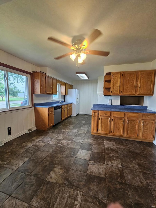 kitchen with brown cabinets, white refrigerator with ice dispenser, ceiling fan, dark countertops, and open shelves