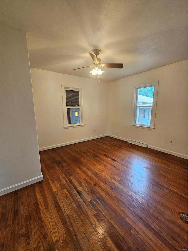 empty room featuring dark wood-type flooring, baseboards, a ceiling fan, and a baseboard heating unit