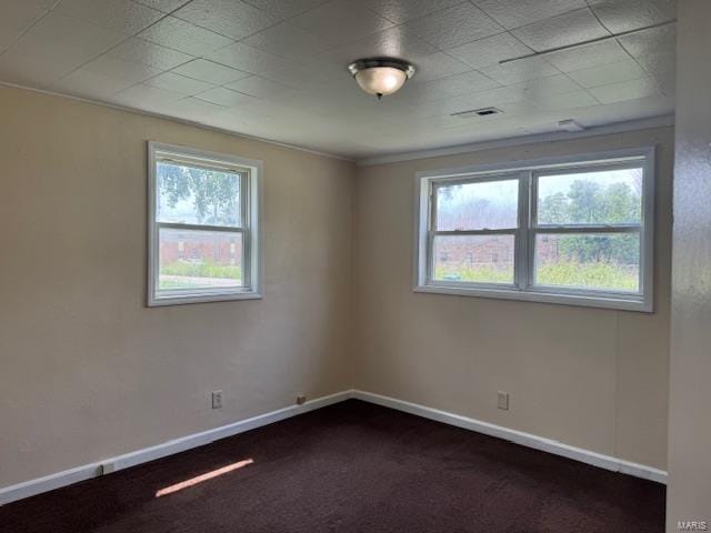 spare room with baseboards and dark colored carpet