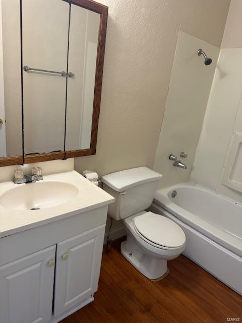 bathroom with wood finished floors, vanity, toilet, and bathtub / shower combination