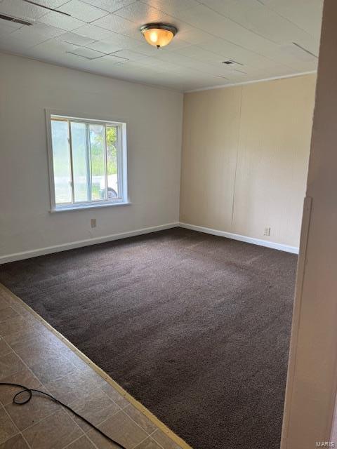 unfurnished room with baseboards and dark colored carpet