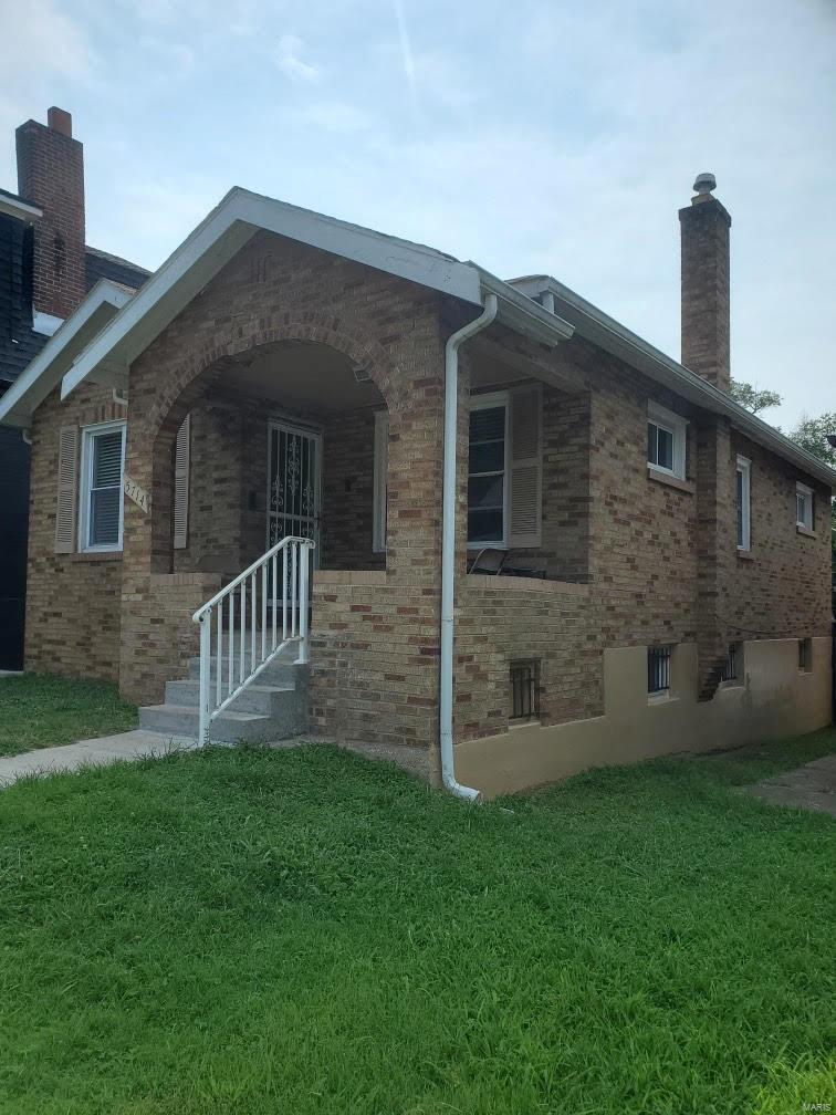 5714 Pamplin Pl, Saint Louis, MO 63136 - view of side of property featuring brick siding, a lawn, and a chimney