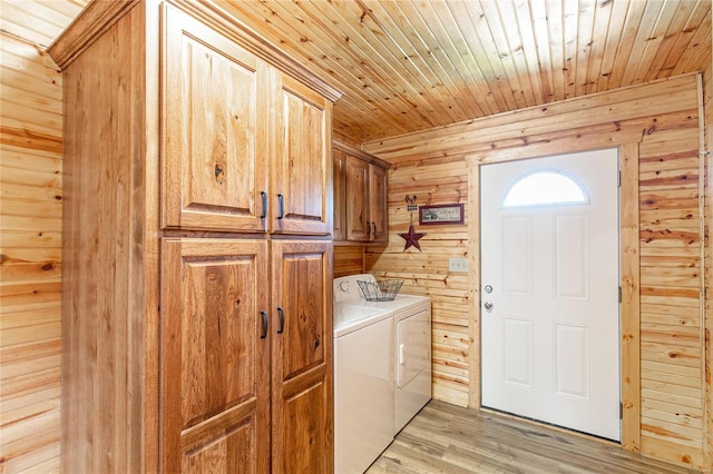clothes washing area featuring cabinet space, independent washer and dryer, wood walls, wooden ceiling, and light wood-style flooring