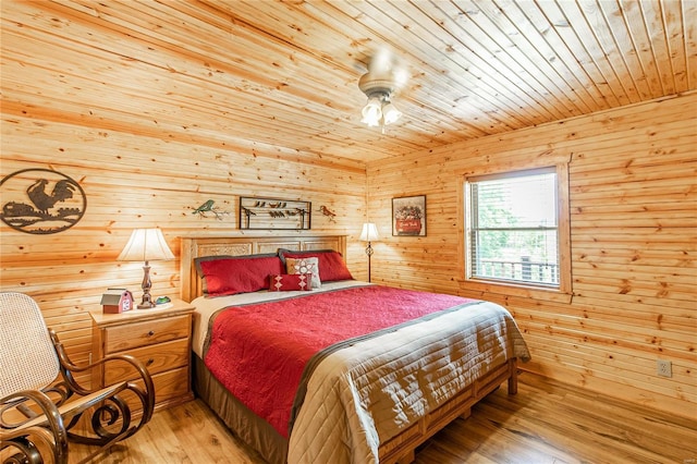 bedroom with wooden ceiling, wood walls, hardwood / wood-style flooring, and a ceiling fan