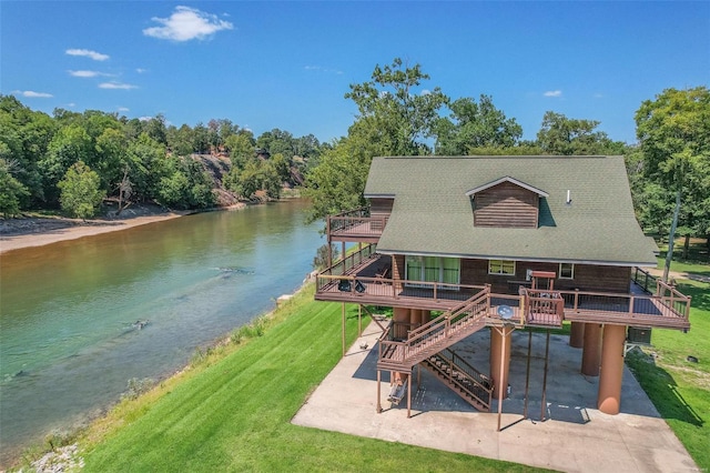rear view of house with a patio, stairs, a lawn, a deck with water view, and driveway
