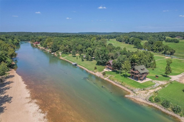 drone / aerial view of a nearby body of water and a heavily wooded area